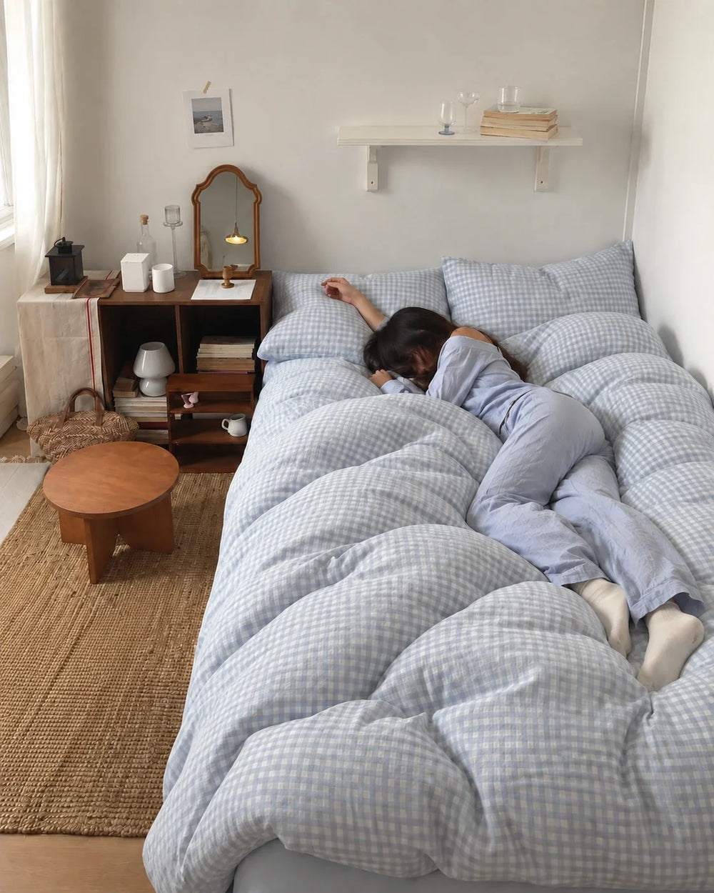 A woman resting on a bed with pale blue checked bedding.