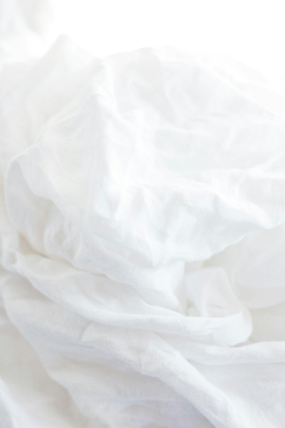 Soft white bedding folded in bright natural light.
