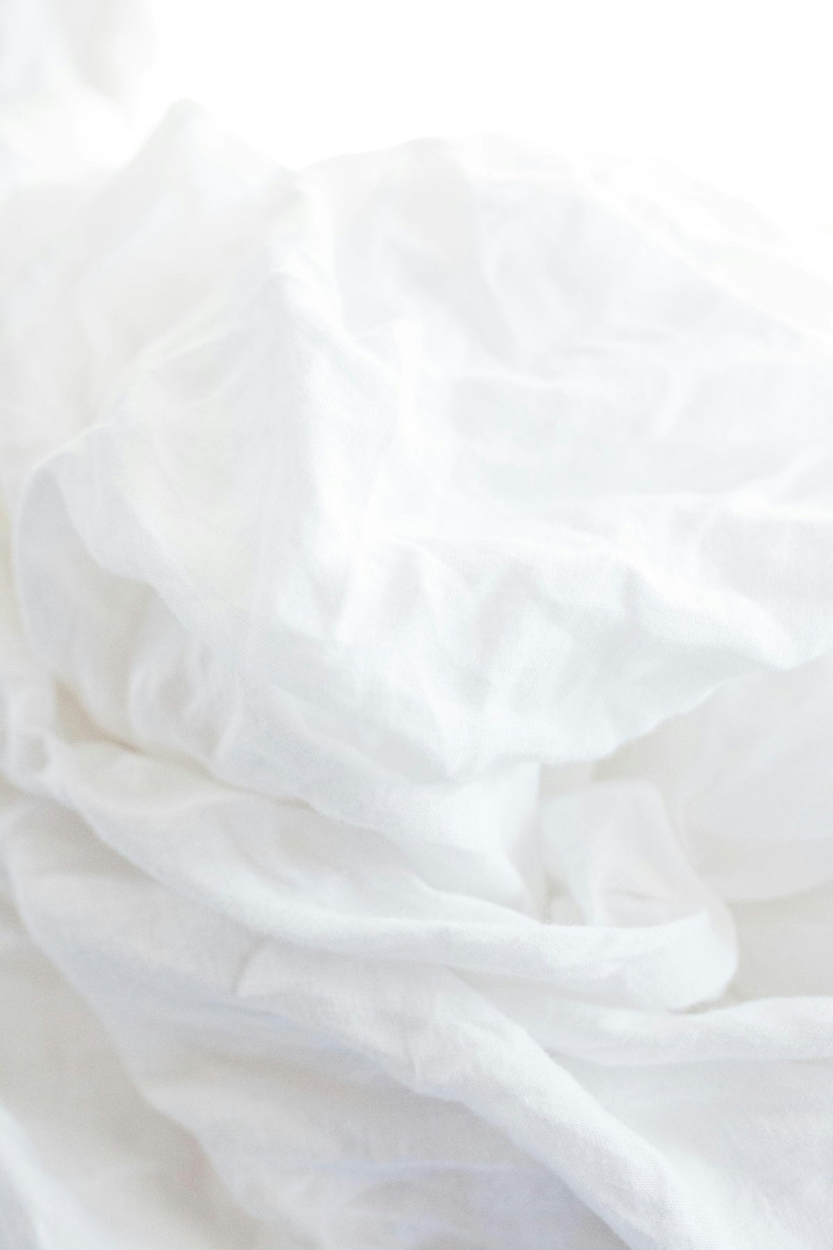 Soft white bedding folded in bright natural light.